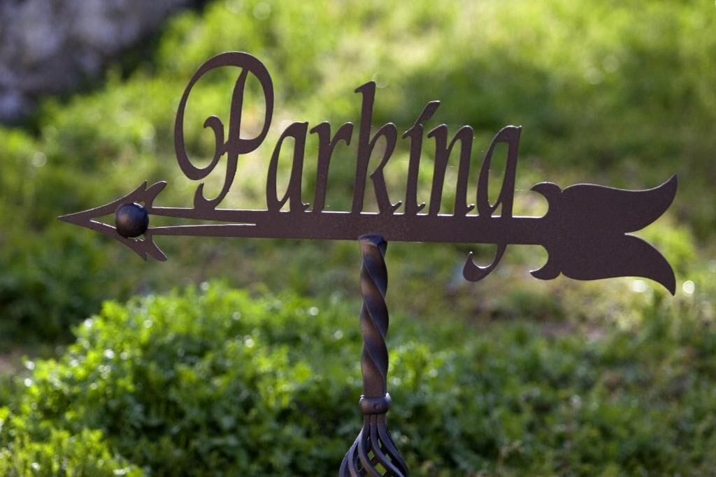 A metal sign with the word "Parking" and directional arrows.
