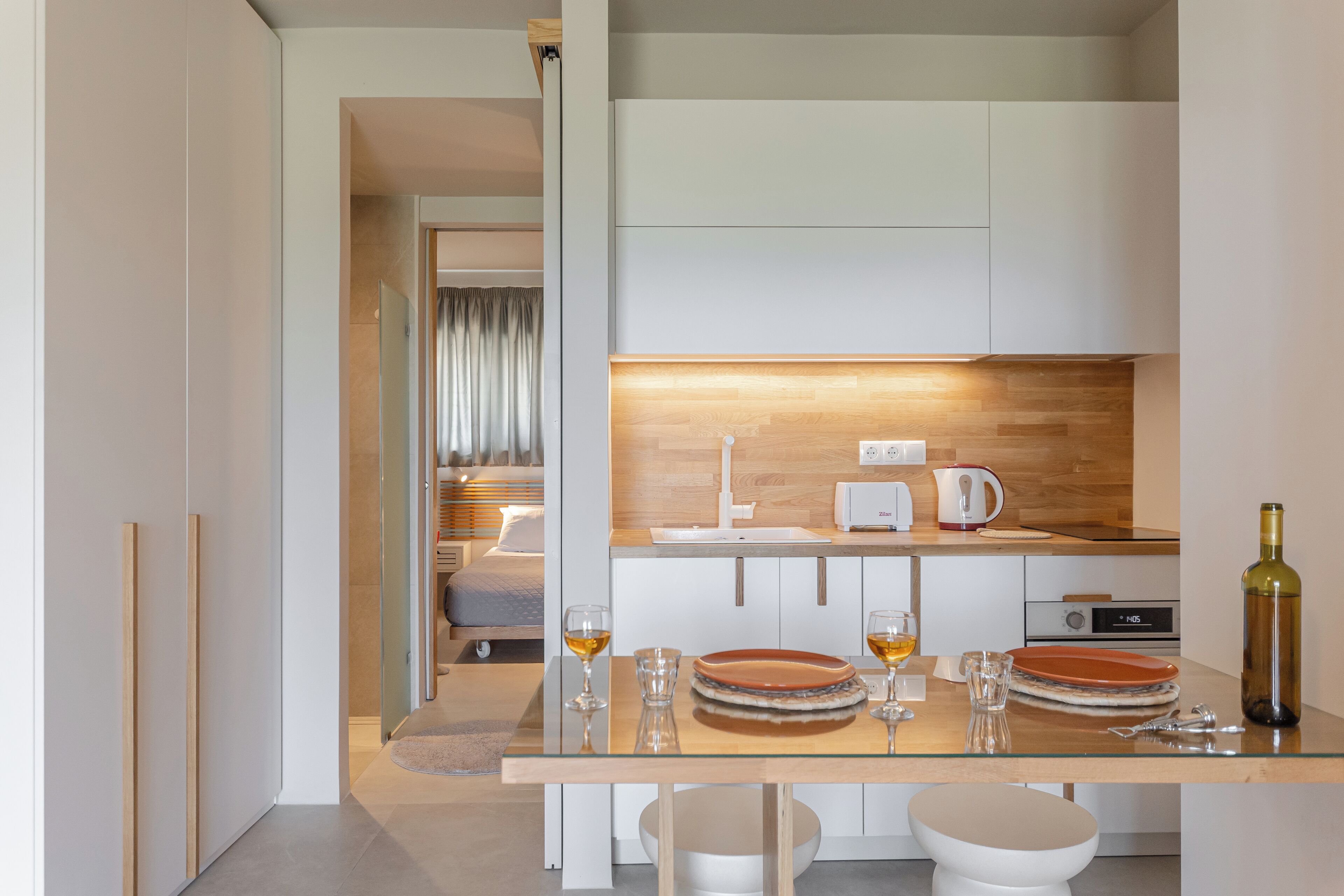 Cocina moderna con encimera de madera, un lavamanos, un hervidor y una botella de vino.
