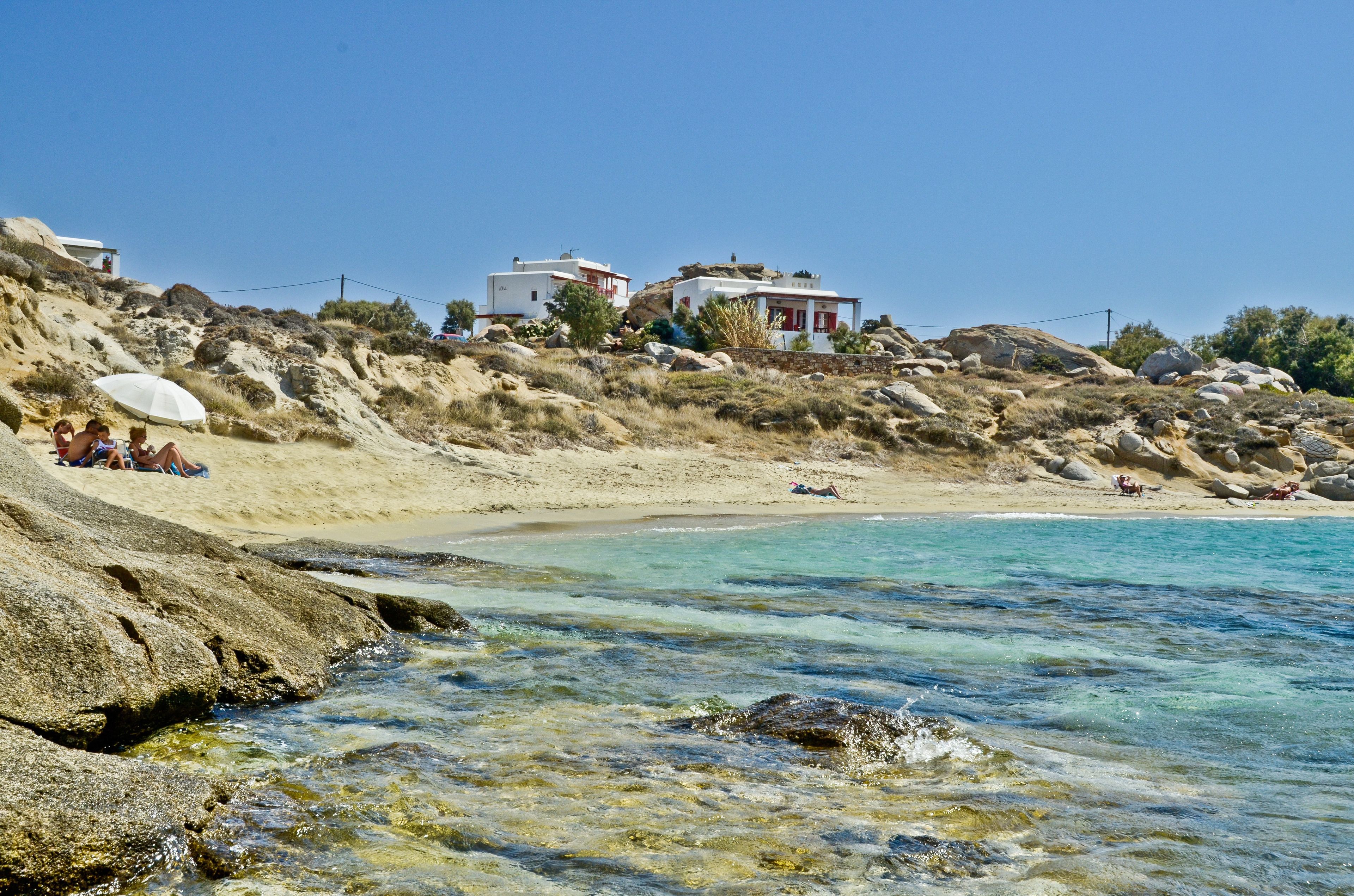 A coastal area with clear waters, rocky terrain, and buildings with red and white facades.