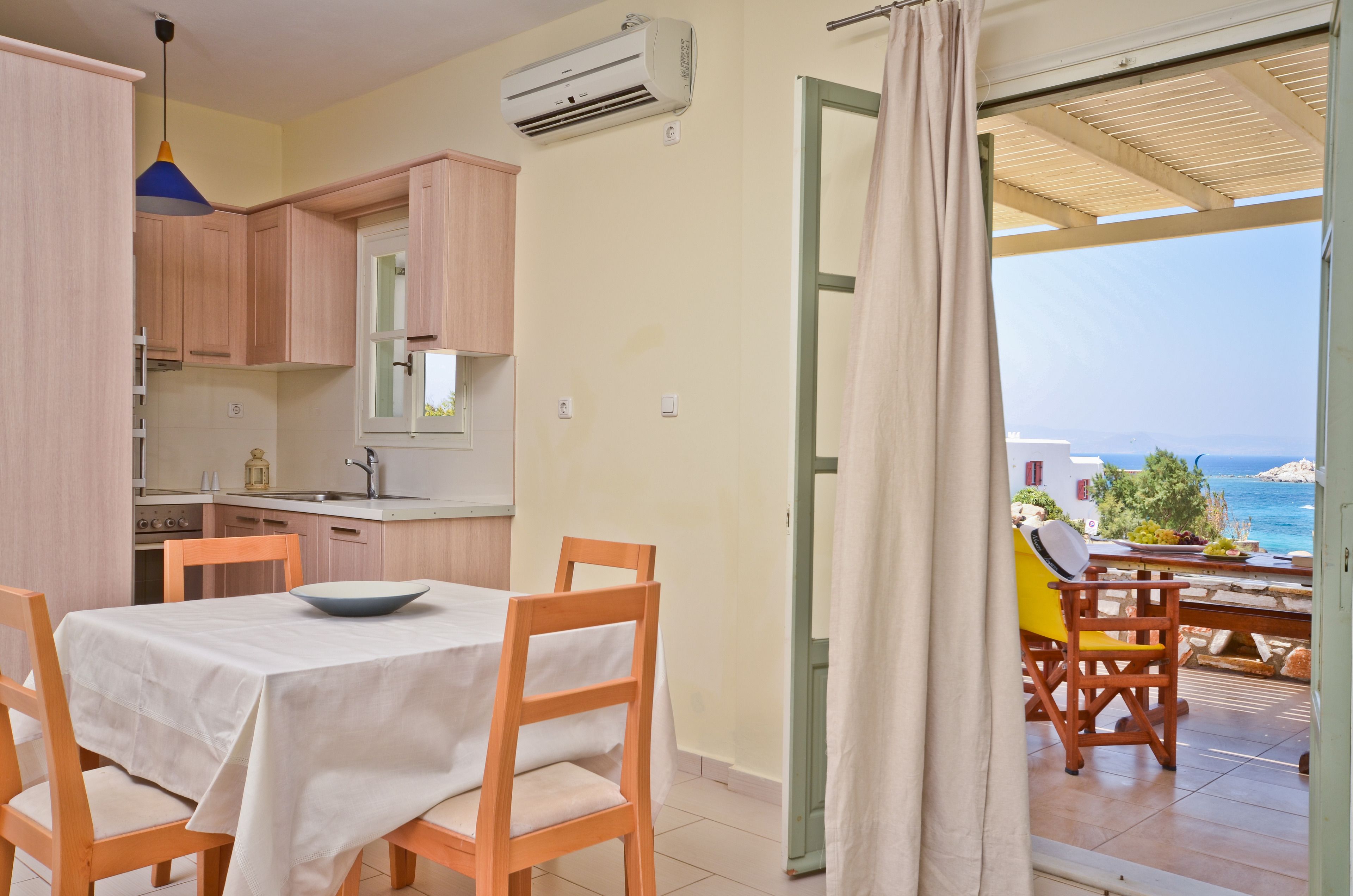 A kitchen with wooden cabinets, a dining table with chairs, and an air conditioner.