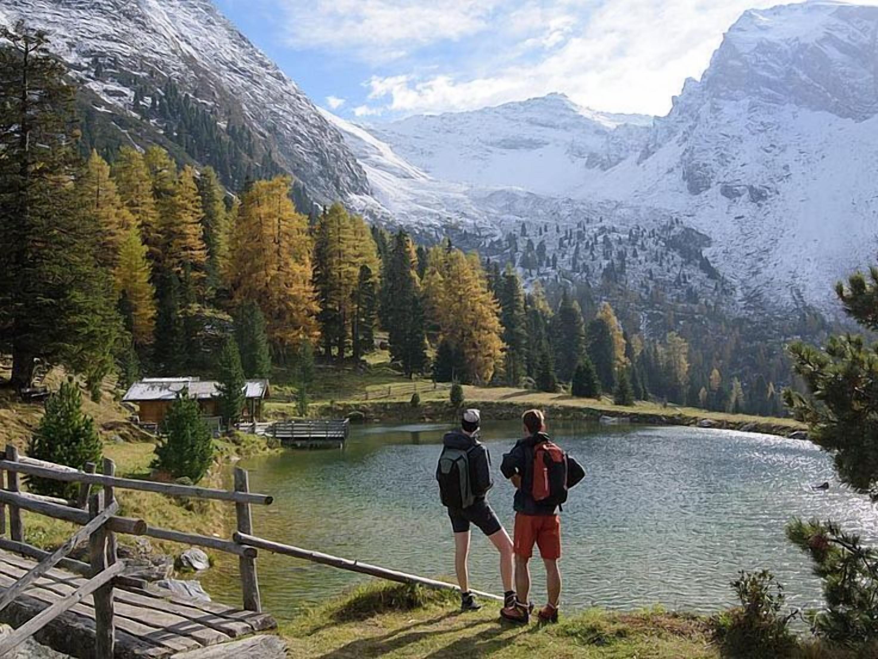 Ein See mit einer Holzterrasse und einer kleinen Holzhütte im Hintergrund.