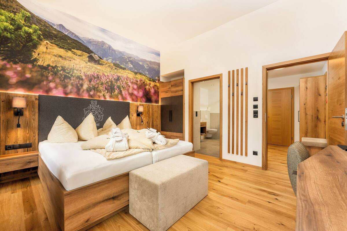Ein modernes Schlafzimmer mit einem Holzbett, einem großen Wandgemälde und Holzböden.