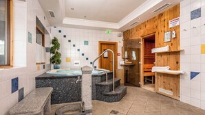 A modern bathroom with a stone bench, a sink, and a wooden sauna area.