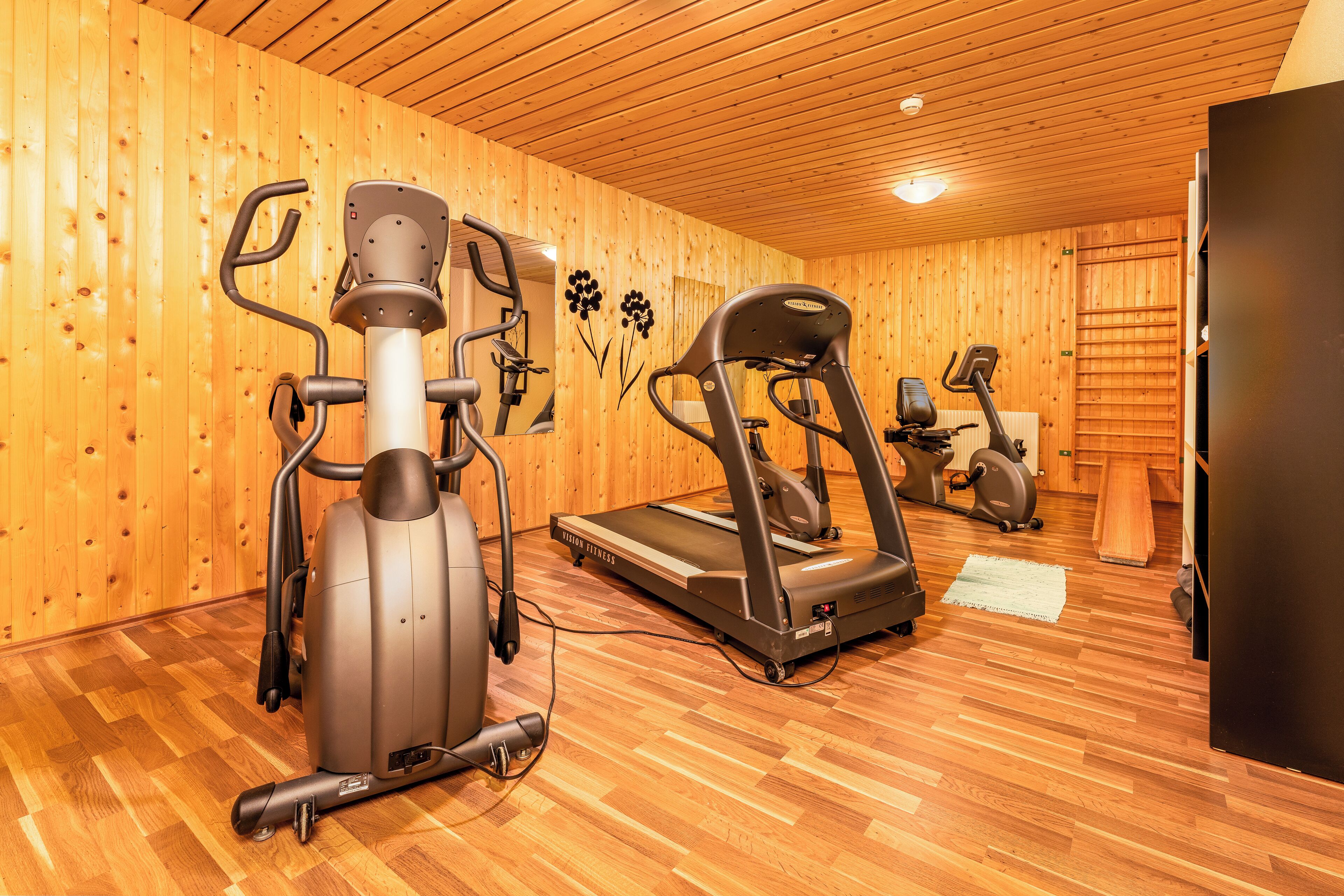 Una palestra con attrezzature per esercizi, pareti e pavimento in legno.