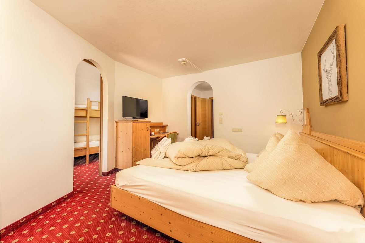 Ein Hotelzimmer mit einem Einzelbett, einem Fernseher, einem Schreibtisch und einem Kleiderschrank.