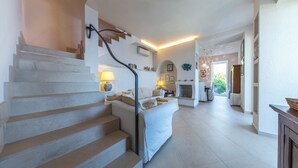 Un escalier menant à un espace de vie comprenant un canapé, des lampes et une cheminée.