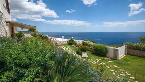 Une propriété située sur la côte, dotée d’un mur en pierre, d’une pergola et offrant une vue sur la mer.