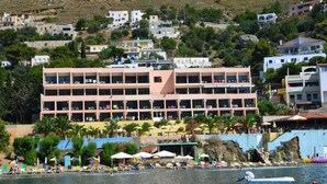 A coastal hotel with multiple floors, outdoor seating, and a beach view. - Hotel Plaza (Kalymnos)
