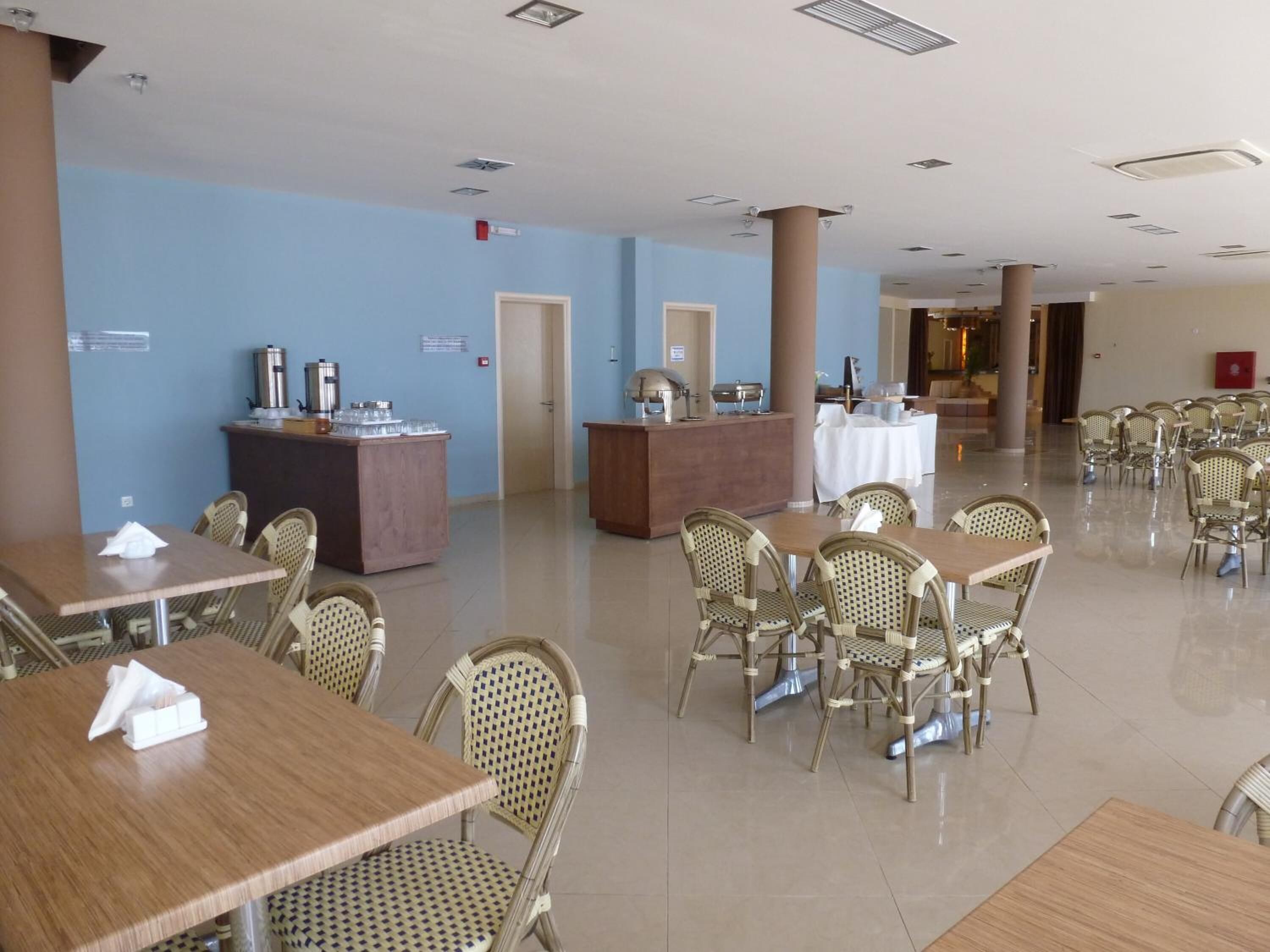A spacious dining area with multiple tables and chairs, a buffet station, and a reception desk.