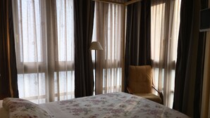 Una habitación de hotel con una cama, una silla y cortinas.