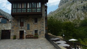 Un edificio de piedra con balcón, puerta de madera y un cartel que indica un restaurante.