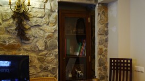 Un mostrador de recepción con un fondo de pared de piedra, una puerta de madera, una estantería y un monitor de computadora.