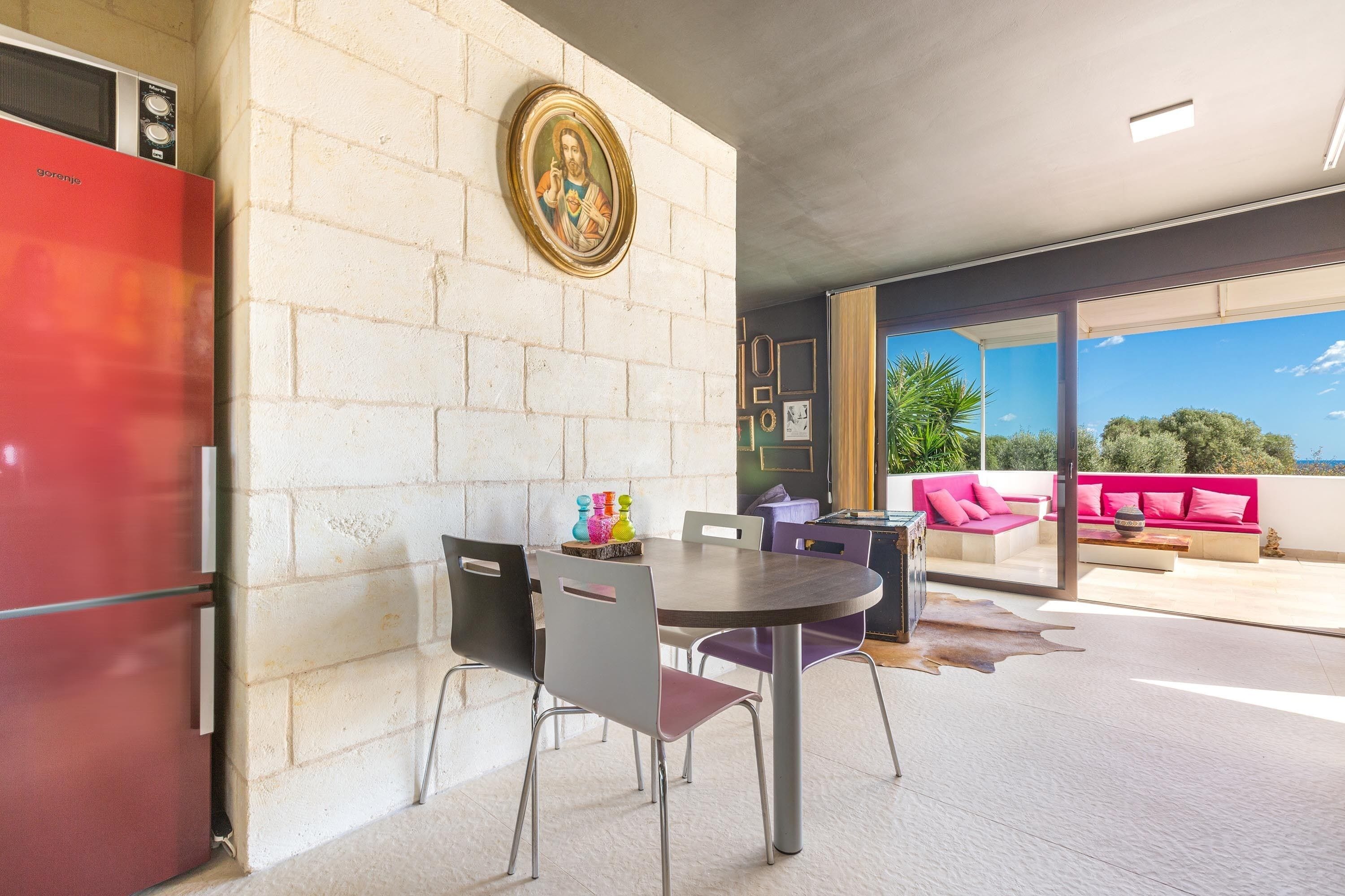 Un coin repas avec un mur en briques, un réfrigérateur rouge et une table avec des chaises.