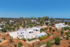 A modern villa with a pool, surrounded by greenery and solar panels. - Villa Karma (Carovigno)