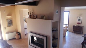 A living room with a fireplace, a sofa, a coffee table, and a dining area with a table and chairs. - La Quercetta (Foligno)