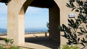 A covered outdoor area with a view of a cityscape, a sign reading "La Querelle," and a potted plant. - La Quercetta (Foligno)