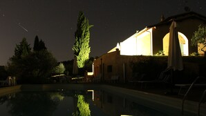 A nighttime pool area with a reflection of trees and a building. - La Quercetta (Foligno)