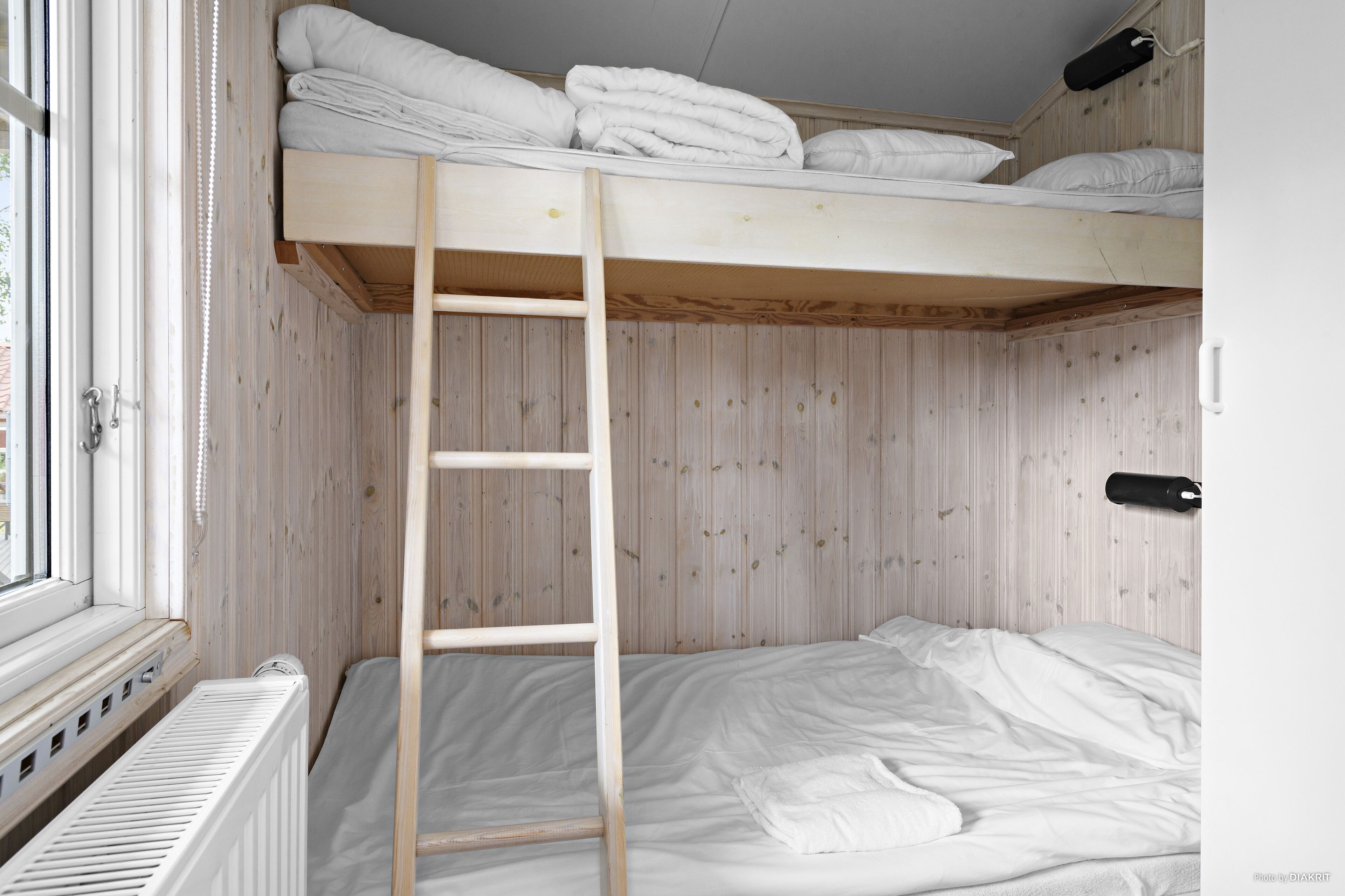 Un letto a castello con una scala in legno, biancheria bianca e una finestra con persiane.