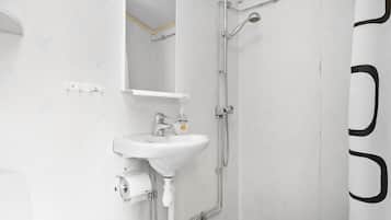 A bathroom with a white sink, mirror, and shower.