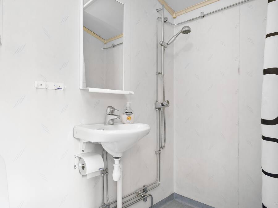 A bathroom with a white sink, mirror, and shower.