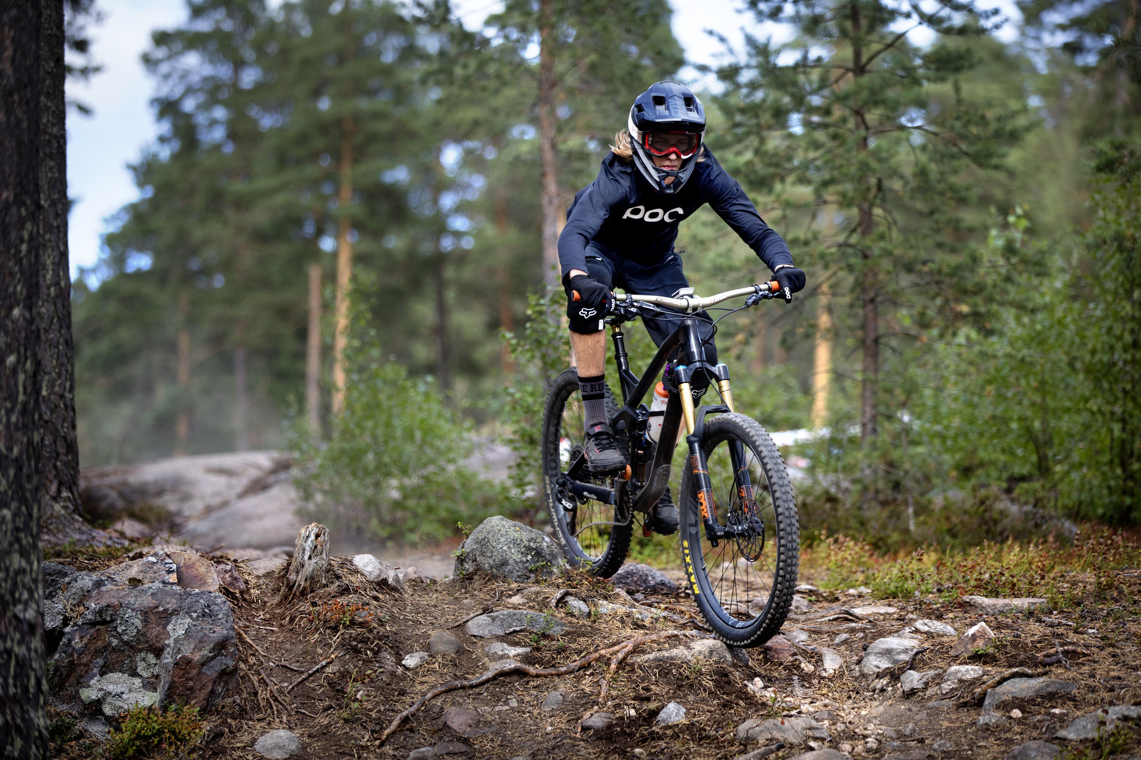 A mountain biker on a trail surrounded by trees.
