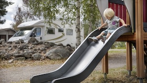 A child on a playground slide with a recreational vehicle in the background. - First Camp Lugnet Falun (Falun)