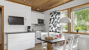 A modern kitchen with white cabinetry, a black countertop, and a wooden ceiling. - First Camp Lugnet Falun (Falun)