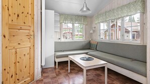 A room with a wooden door, a bench, a table, and a window with a view of houses. - First Camp Lugnet Falun (Falun)