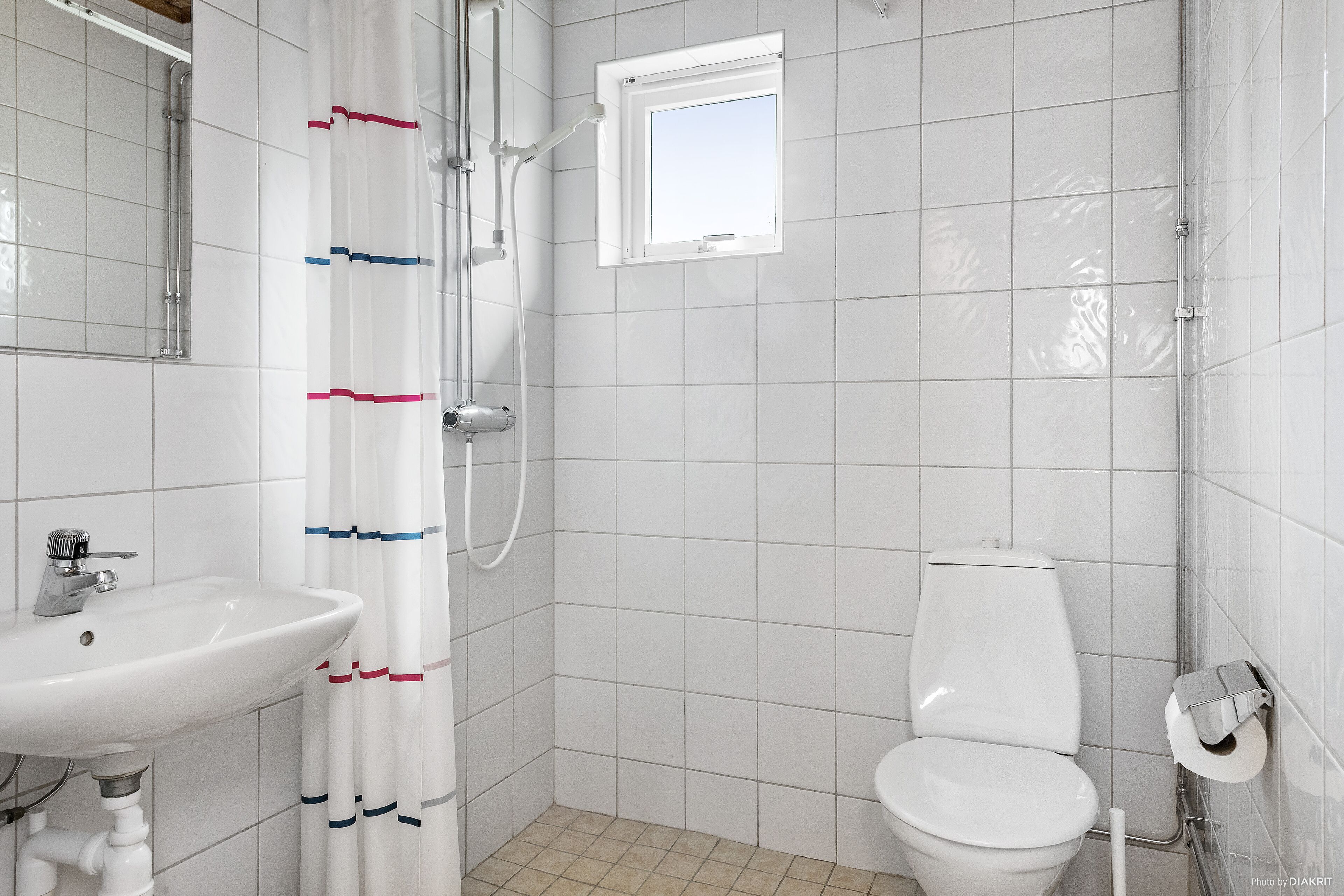 A bathroom with a white sink, toilet, and shower area.