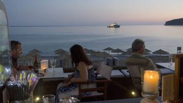 A restaurant with a view of the sea and a ship in the distance.