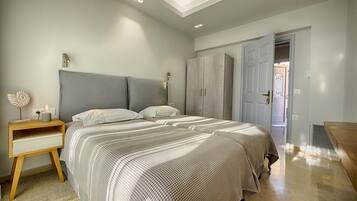 Une chambre à coucher avec un grand lit, une table de chevet, une armoire et une porte donnant sur une autre pièce.