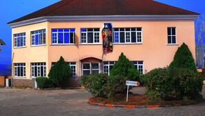 A two-story building with a reception area, a red roof, and a sign indicating a cinema. - Jorany Hotel Resort Ikom (Ikom)