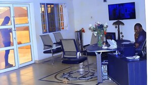 A modern living room with a dining area, a TV mounted on the wall, and a large window with a view. - Jorany Hotel Resort Ikom (Ikom)