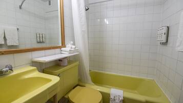 Een badkamer met een geel wastafel, een geel toilet, een bad en een douchegordijn.