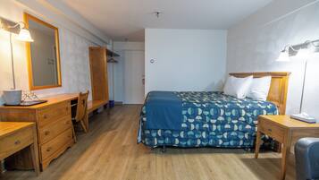 Une chambre à coucher avec un lit, une commode en bois, un bureau et une chaise.