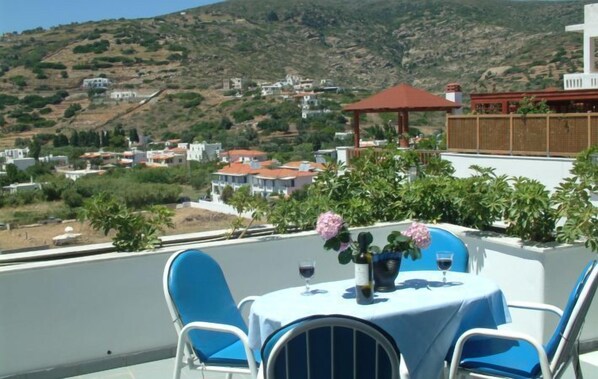 A terrace with a table set for two, overlooking a hillside village.