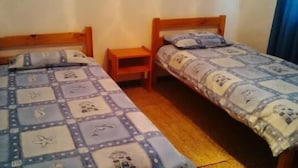 Two single beds with wooden headboards, a small wooden nightstand, and a patterned bedspread. - Holiday House Sedgefield (Sedgefield)