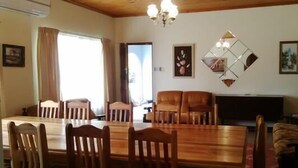 A dining area with a wooden table and chairs, a television, and a sofa. - Holiday House Sedgefield (Sedgefield)