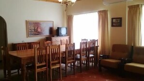 A dining area with wooden furniture, a television on a cabinet, and a painting on the wall. - Holiday House Sedgefield (Sedgefield)