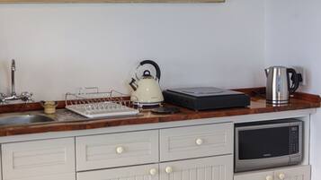 Una cocina con microondas, hervidor y cafetera en la encimera.