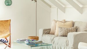 A modern living room with a glass coffee table, a beige sofa with patterned cushions, a wooden chair, and a globe decoration on the wall. - SaWestCoast & Beyond (Paternoster)