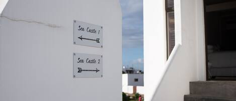 Un mur sur lequel sont fixées deux panneaux indicateurs, l’un pointant vers « Sea Castle 1 » et l’autre vers « Sea Castle 2 ».