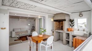 A modern kitchen with a built-in oven, a sink, and a dining area with a wooden table and chairs. - SaWestCoast & Beyond (Paternoster)