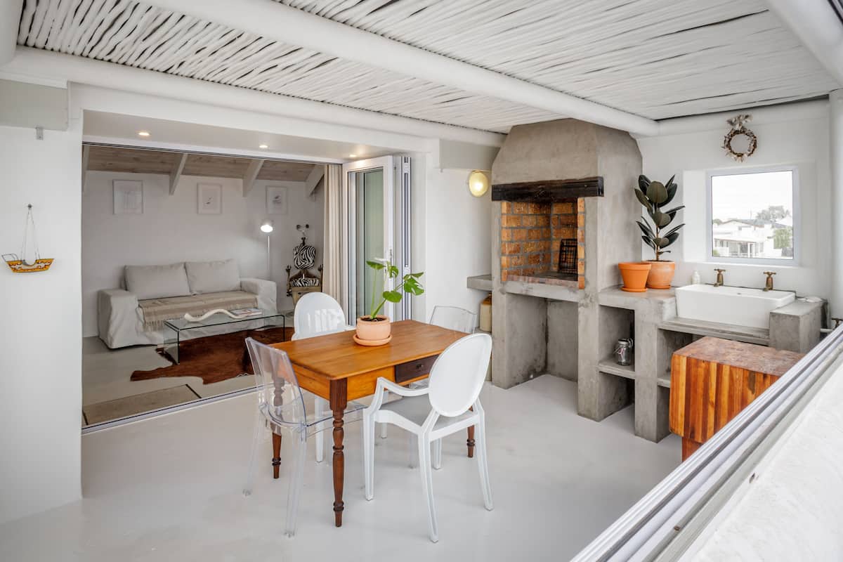 A modern kitchen with a built-in oven, a sink, and a dining area with a wooden table and chairs.