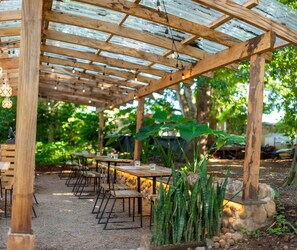 An outdoor patio with wooden tables and chairs, surrounded by greenery and stone accents. - Casa 1800 Suchitoto (Suchitoto)