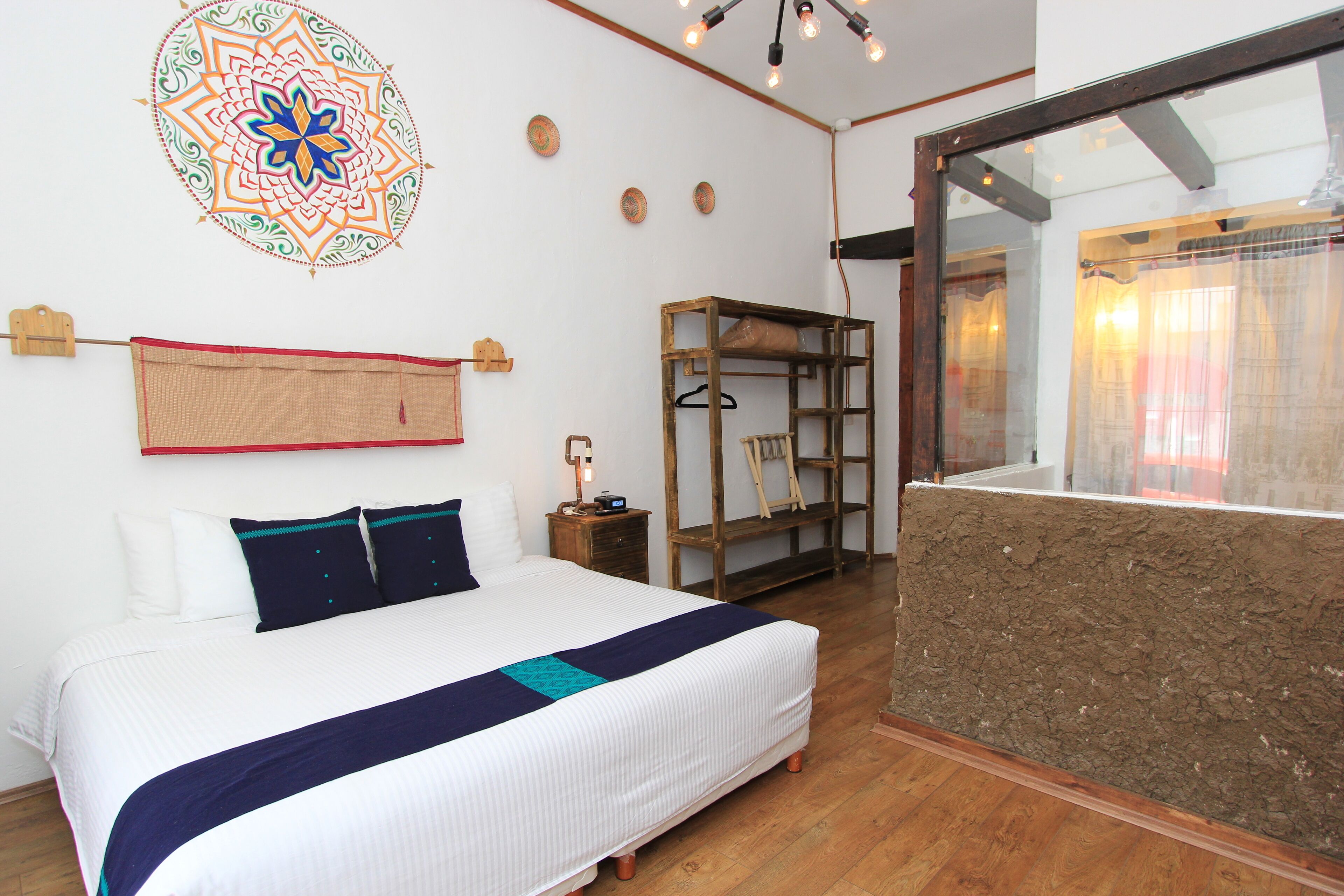 Une chambre à coucher avec un lit, une étagère en bois, un élément de décoration murale et une fenêtre avec des rideaux.
