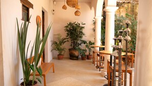 A corridor with potted plants, wooden furniture, and hanging wicker lamps. - Sereno Hotel (San Cristóbal de las Casas)