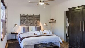 Un dormitorio con cama, mesita de noche, lámpara, armario y un cabecero decorativo.