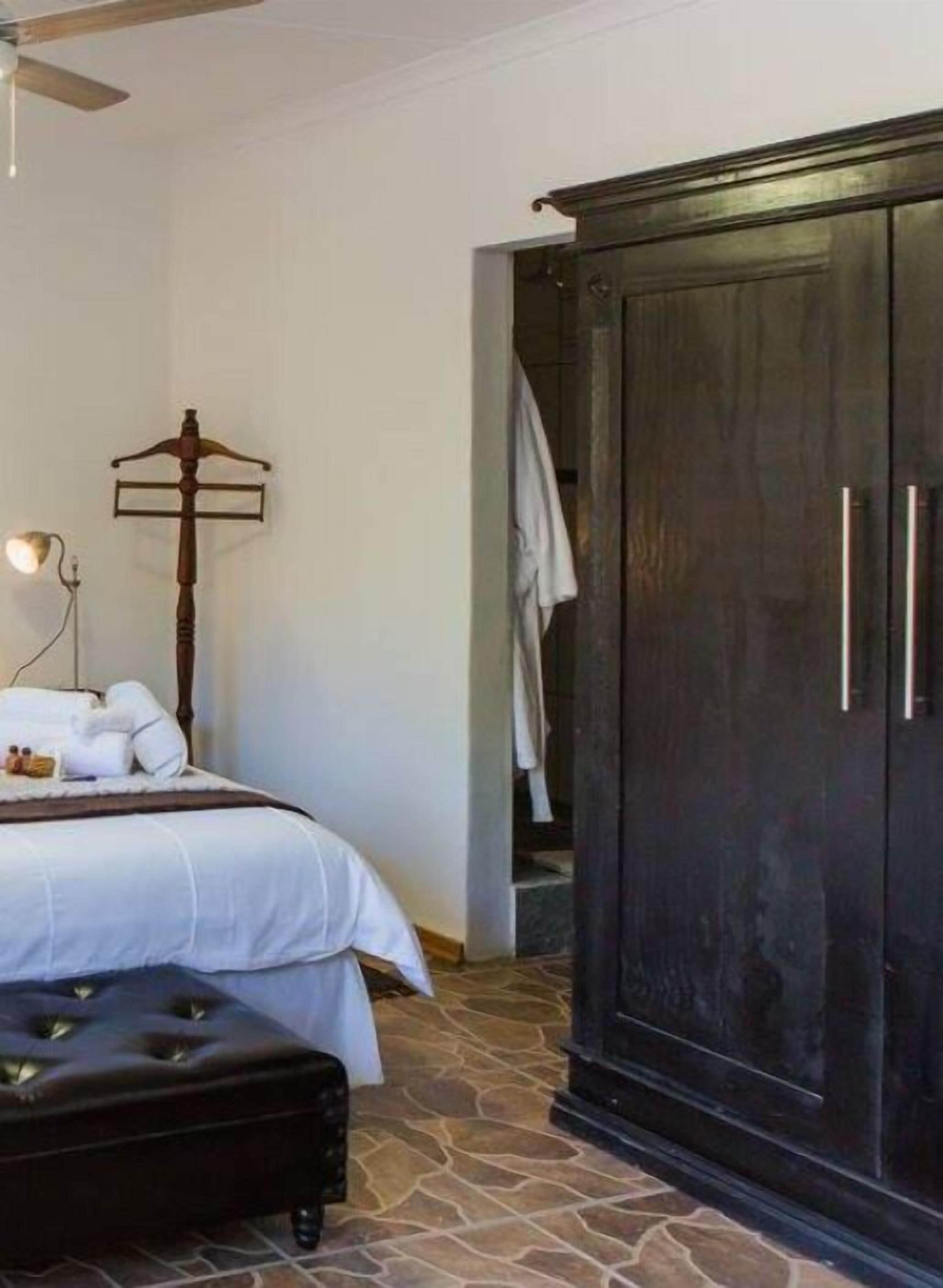 A bedroom with a bed, a wardrobe, a bedside table, and a lamp.