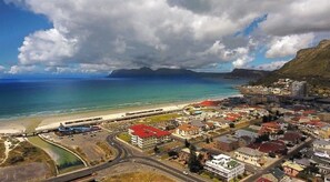 An aerial view of a coastal town with a beach, roads, and buildings.